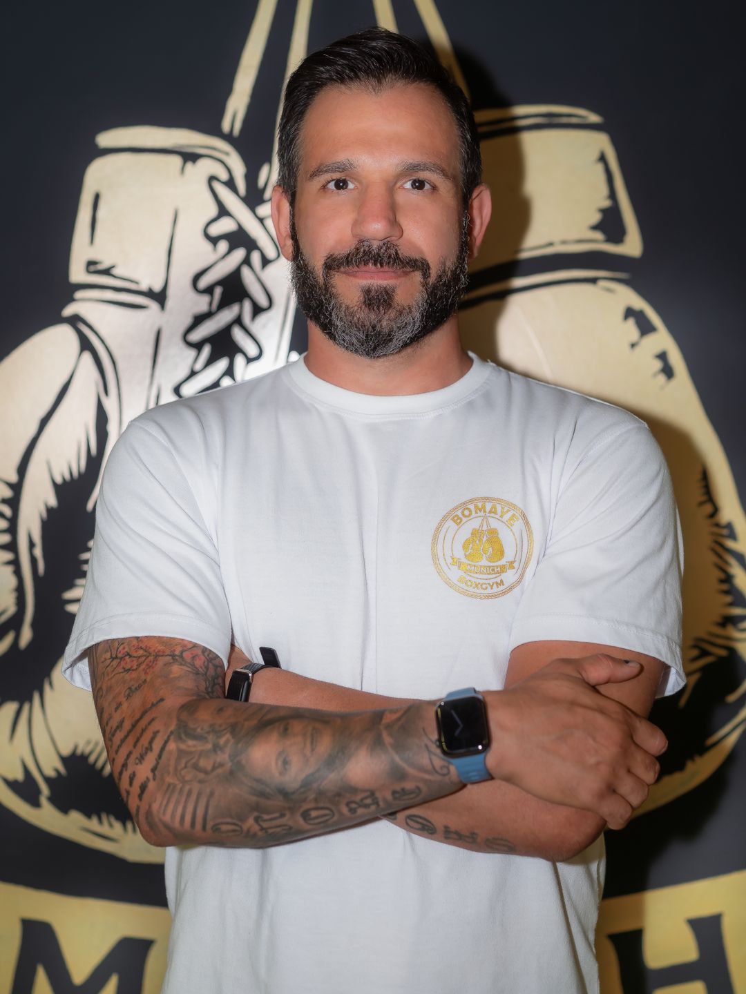 Coach des Bomaye Gym München im Portrait vor der Bomaye-Wand