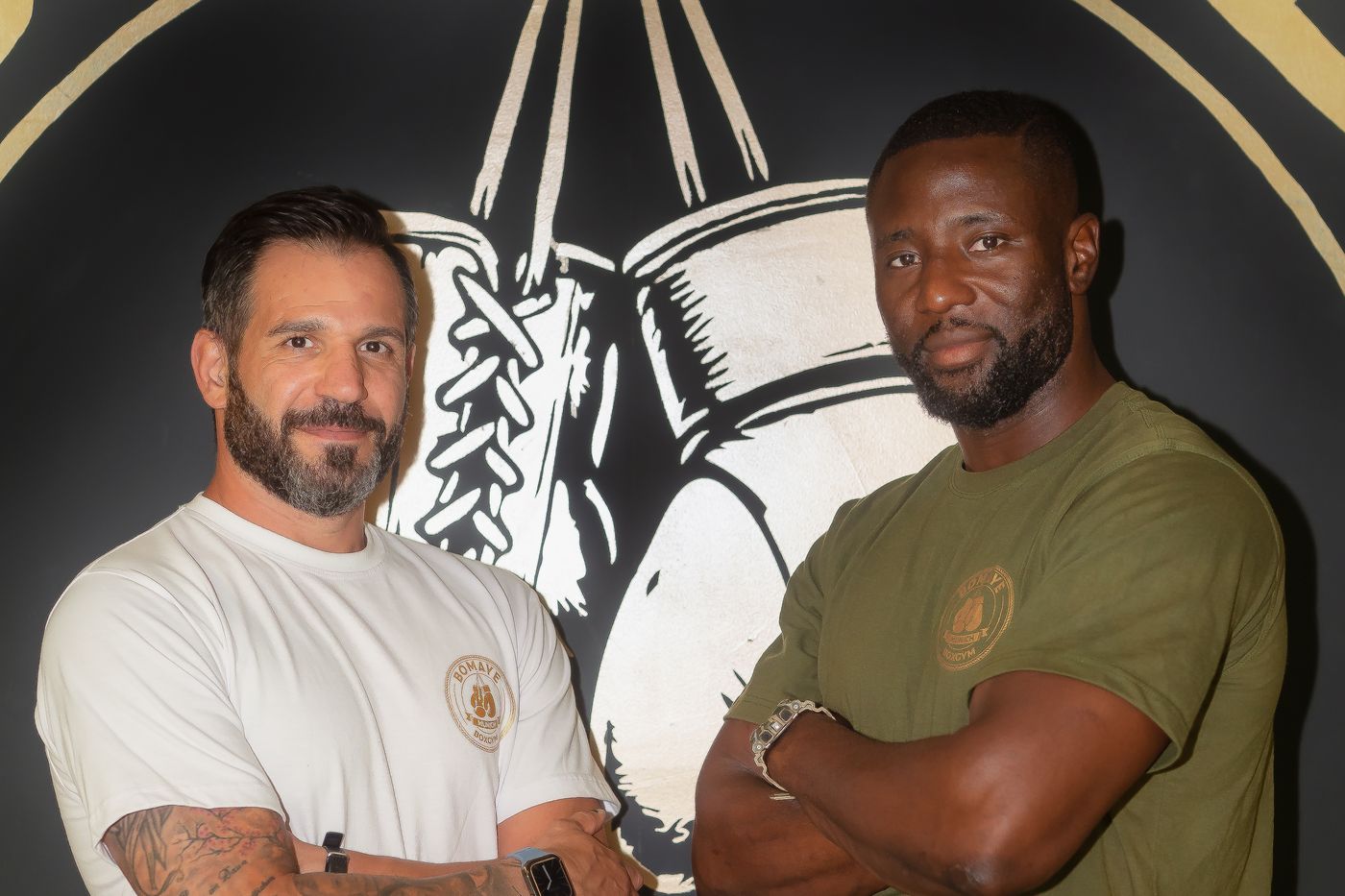 Die beiden Gründer des Bomaye Gym Munich vor der Bomaye-Logowand